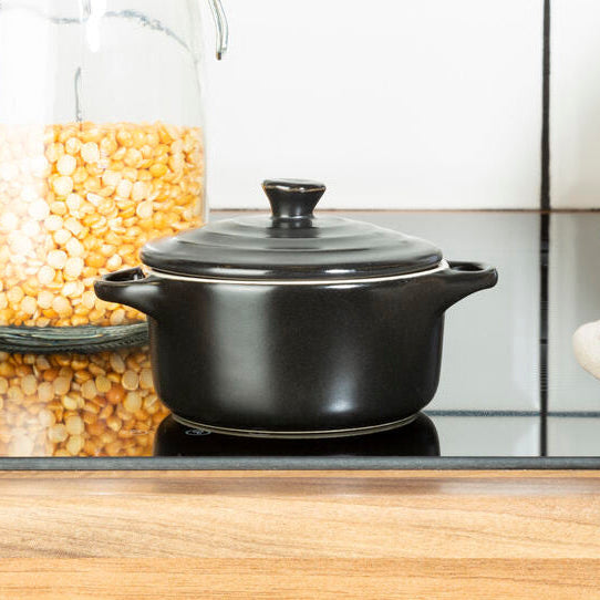 Kitchen counter with jars of pasta and a black pot, tiled wall in the background
