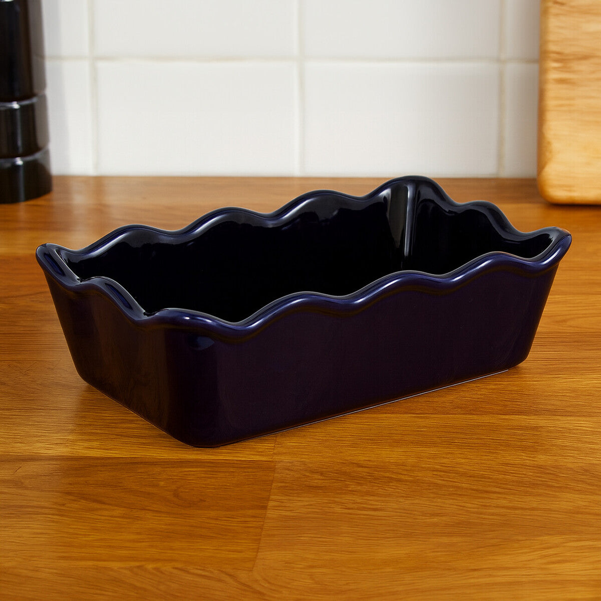 Black rectangular baking dish with wavy edge on a wooden surface
