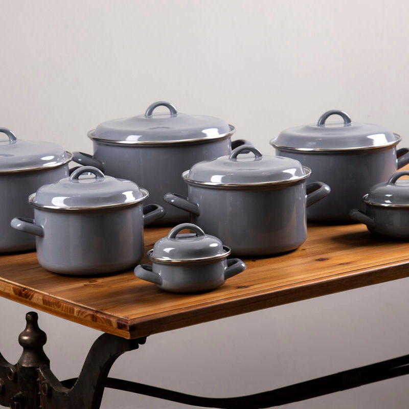 Set of gray enameled cookware on a wooden table with a neutral background