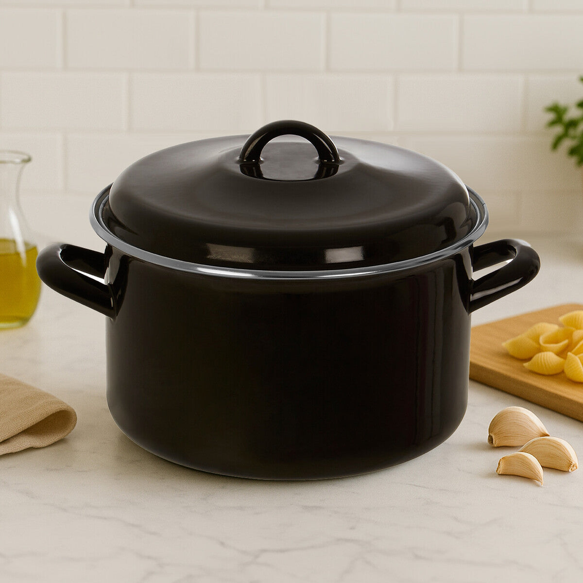 Black enameled cast iron Dutch oven on a kitchen counter with garlic and a cutting board.