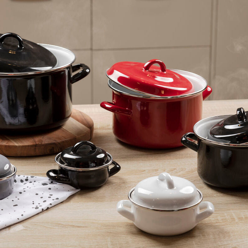 Collection of black, red, and white ceramic cookware on a wooden surface.