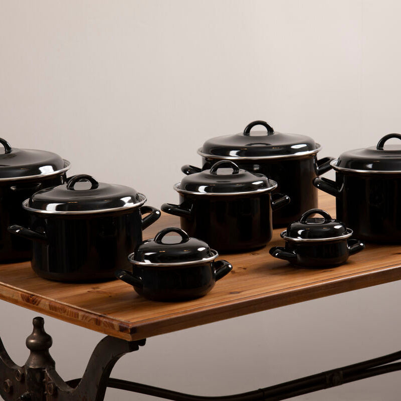 Set of black cookware on a wooden table with a neutral background