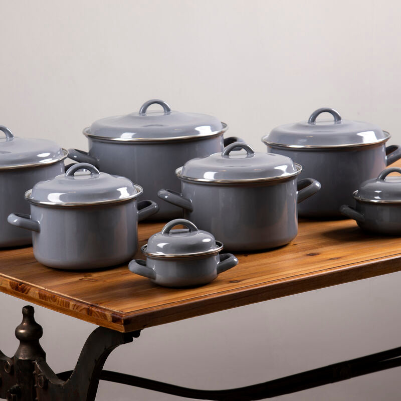 Set of gray enameled cookware on a wooden table with a neutral background