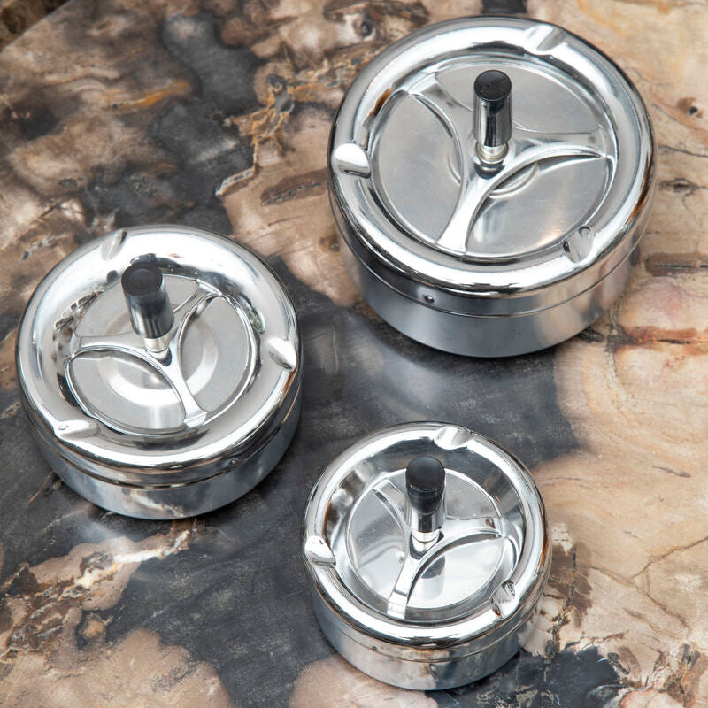 Three metallic kitchen components on a textured surface
