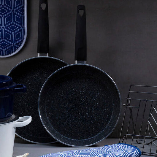Culinary set with pots, pans, and kitchen tools on a gray surface against a dark background