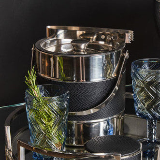 Stainless steel ice bucket with glasses on a dark background