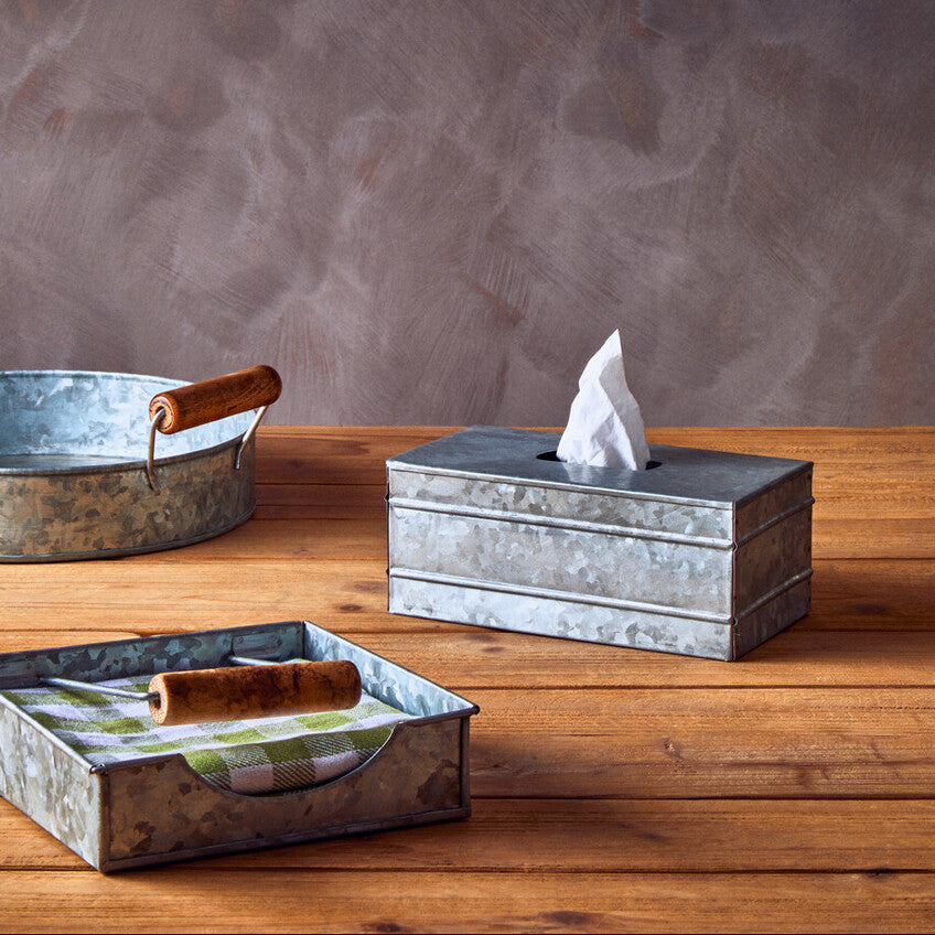 Metal tissue box and tray set on a wooden surface with a gray textured wall background