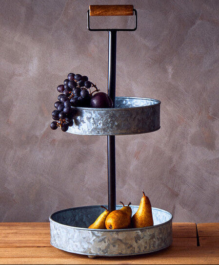 Metal bread basket and tiered stand on a wooden surface with a gray background