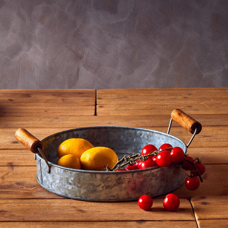 Metal pan with lemons and cherries on a wooden surface