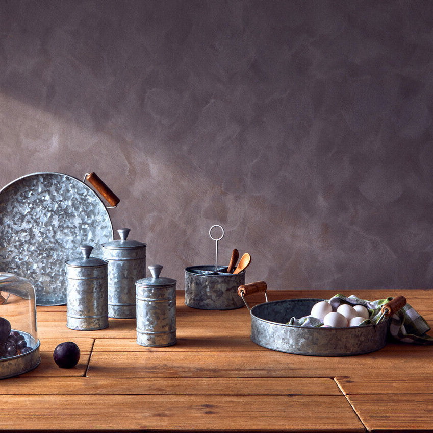 Collection of metal kitchenware on a wooden table with a gray background