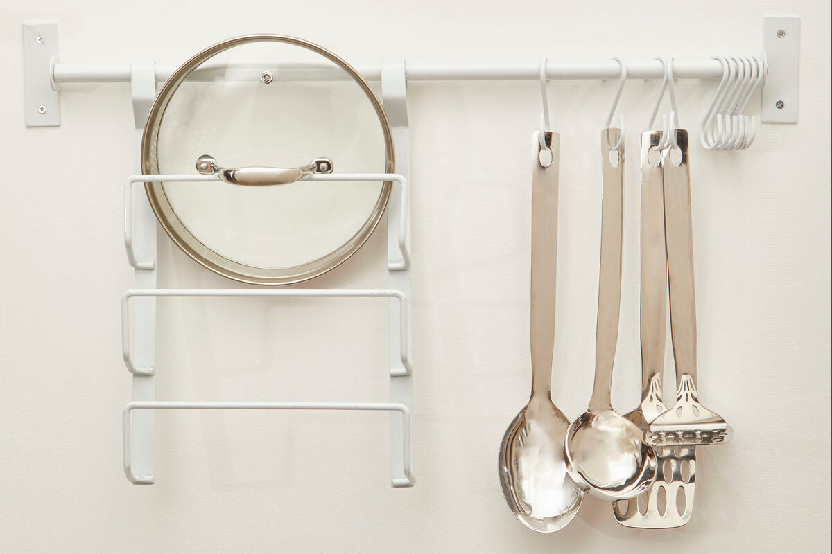 Kitchen utensils hanging on a white wall-mounted rack