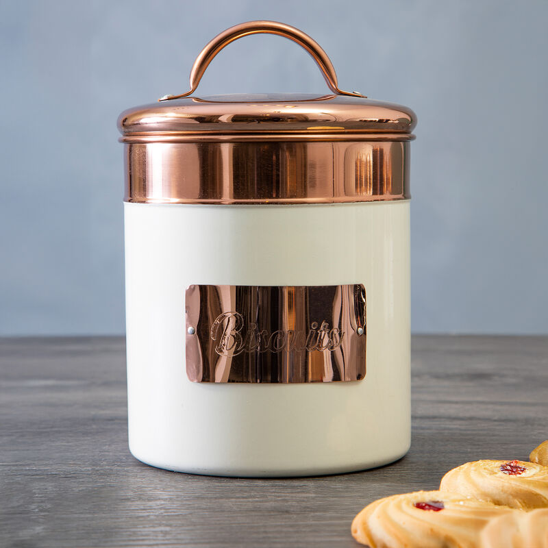 Copper-lidded ceramic jar on a wooden surface with pastries in the background