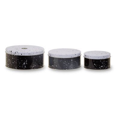 Three black speckled containers with white lids on a white background