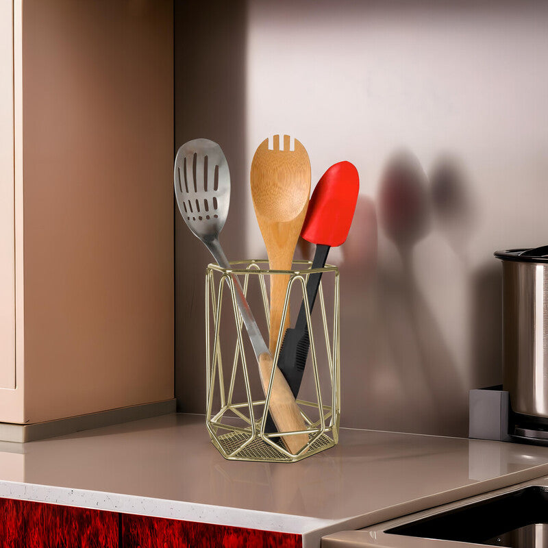 Kitchen utensils in a gold holder on a countertop with a blurred background