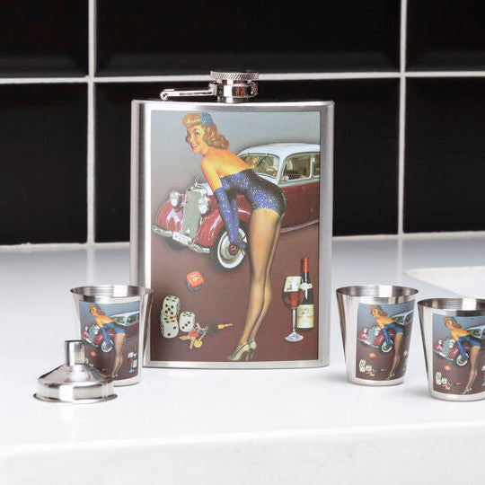Flask and shot glasses with a vintage design on a countertop.
