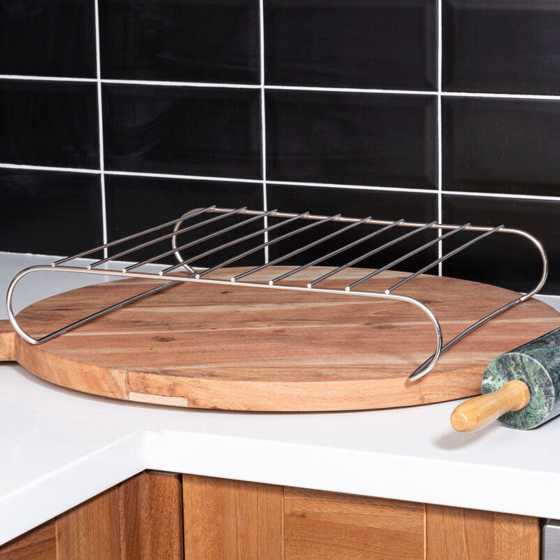 Wooden cutting board with metal rack on a kitchen counter, black tiled wall in the background
