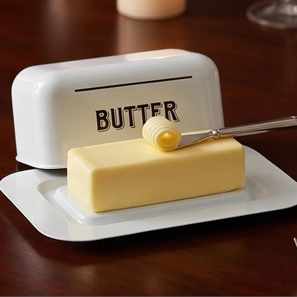 Butter dish with a stick of butter and a knife on a wooden table.