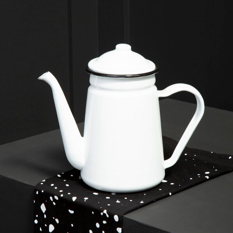 White ceramic teapot on a black surface with a speckled pattern
