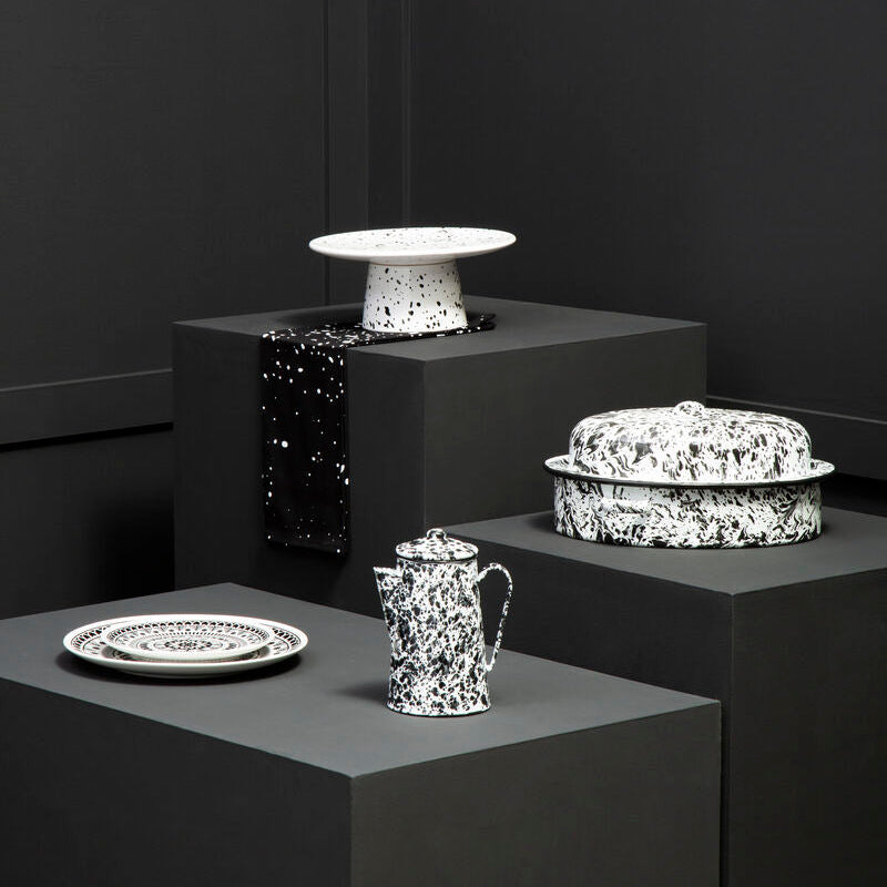 Decorative ceramic items on gray pedestals against a black background