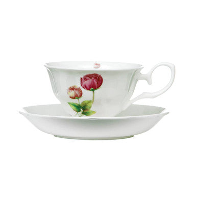 White teacup and saucer with floral design on a white background