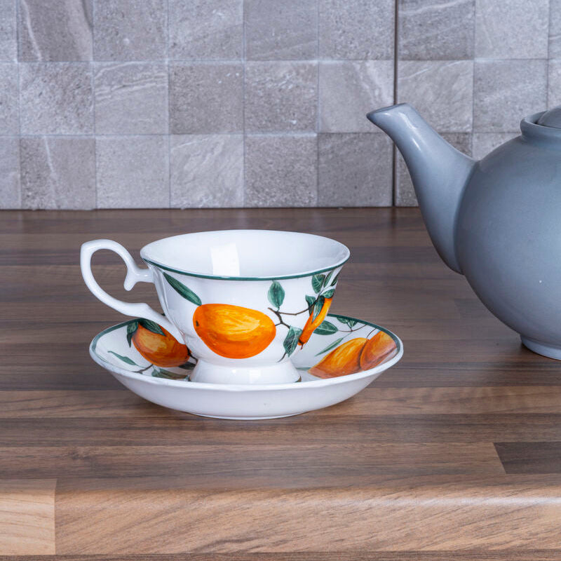 Teacup, saucer, and teapot on a wooden surface with a tiled wall background