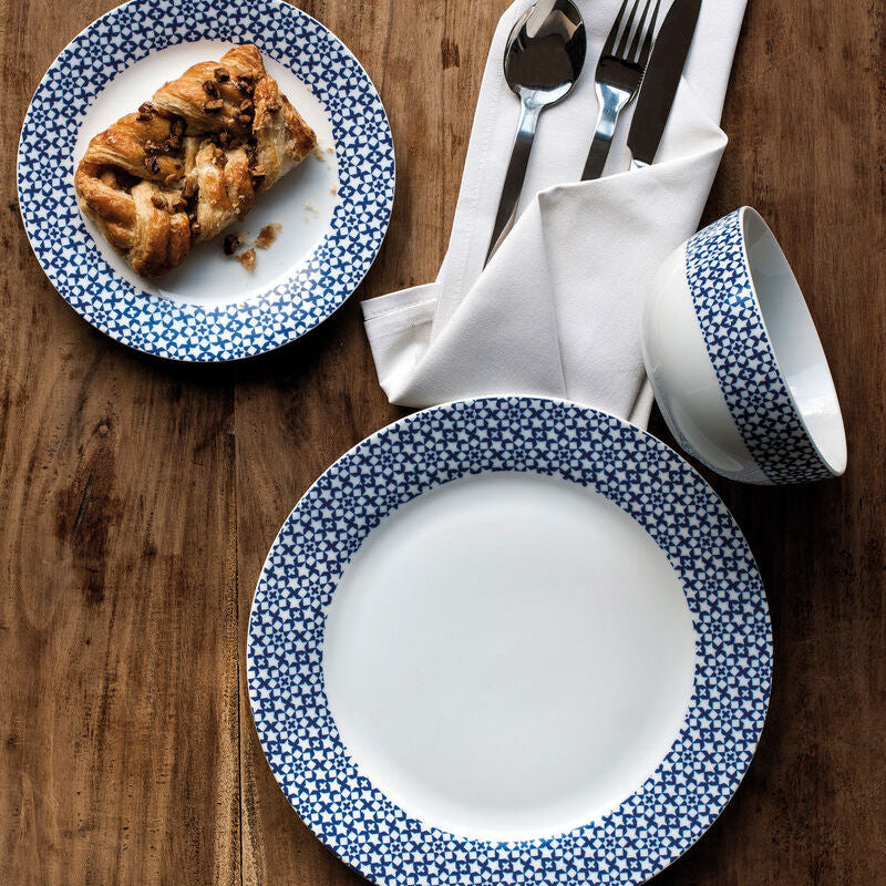 Dinner set with blue floral rim on plates, cup, and cutlery on a wooden surface