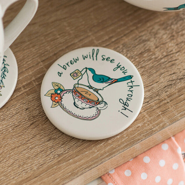 Round coaster with a teacup design and text on a wooden surface.