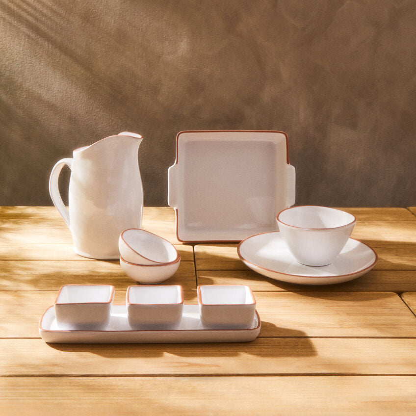 Set of white ceramic dishes on a wooden surface with a neutral background