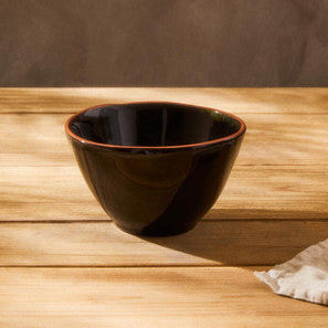 Black ceramic bowl on a wooden surface with a brown background
