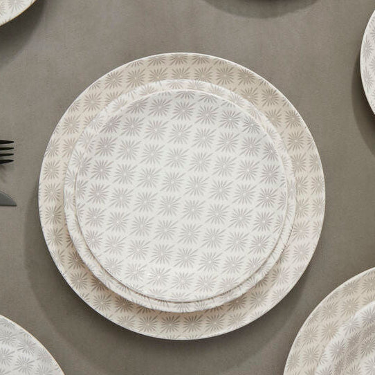 Set of white textured plates and silverware on a brown surface