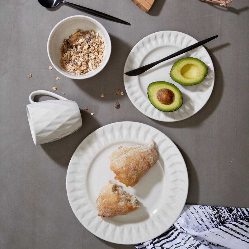 Breakfast setting with pastries, avocado, and coffee on a gray surface