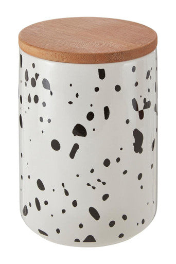 White storage jar with black speckles and a wooden lid on a white background