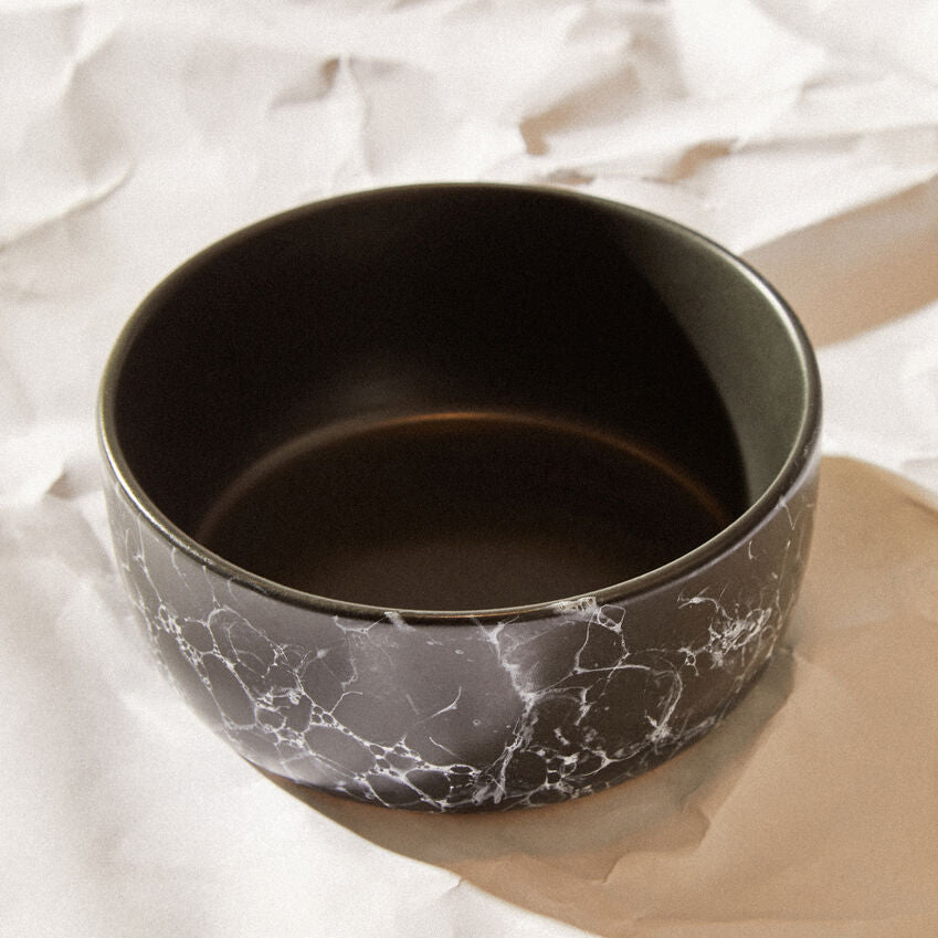 Black marble-patterned bowl on a light fabric background