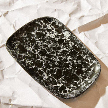 Black and white marbled rectangular object on crumpled white paper