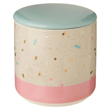 Cylindrical container with a light blue top and pink bottom, featuring a pattern of small colorful shapes on a beige background.