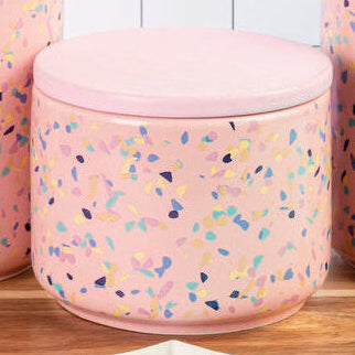 Set of three pink textured jars with a wooden tray on a checkered background