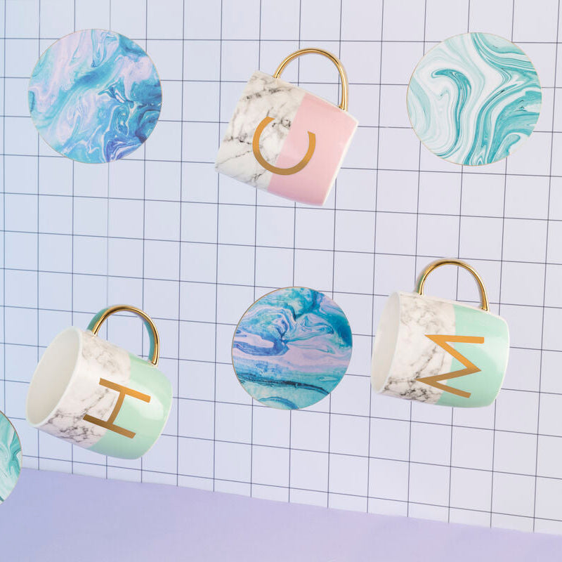 Set of ceramic mugs with marbled designs and gold lettering on a checkered background