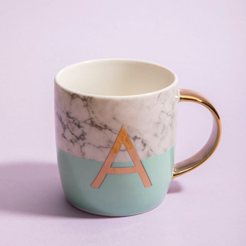 Mug with marble design and gold handle on a light purple background