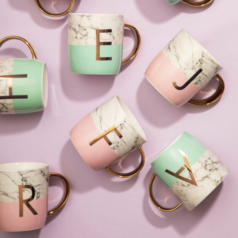 Set of mugs with letter designs on a pink background