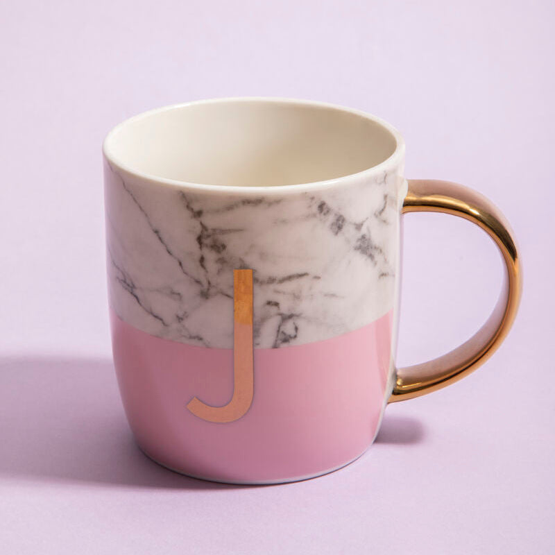 Marble-patterned mug with pink base and gold handle on a light purple background