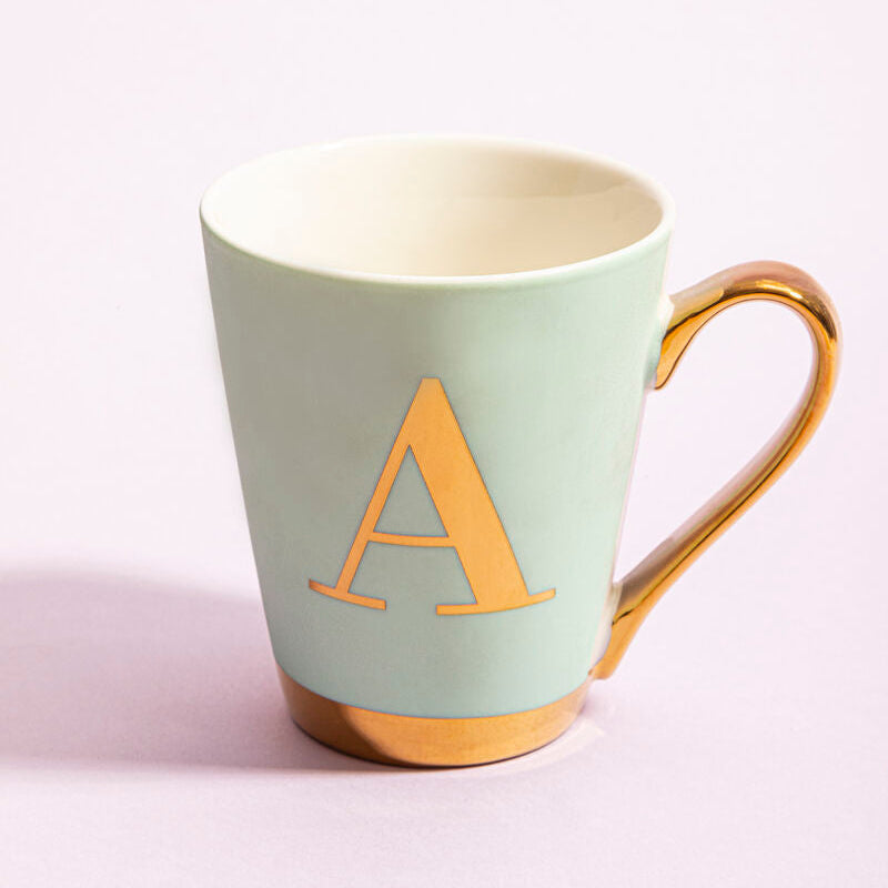 Mint green mug with gold handle and letter &