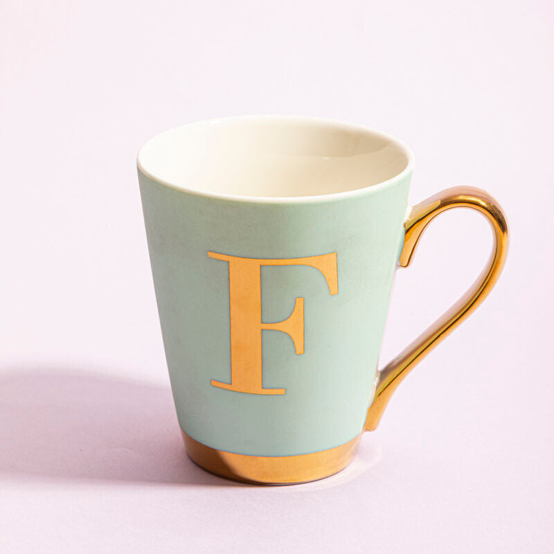 Mint green mug with gold handle and letter &