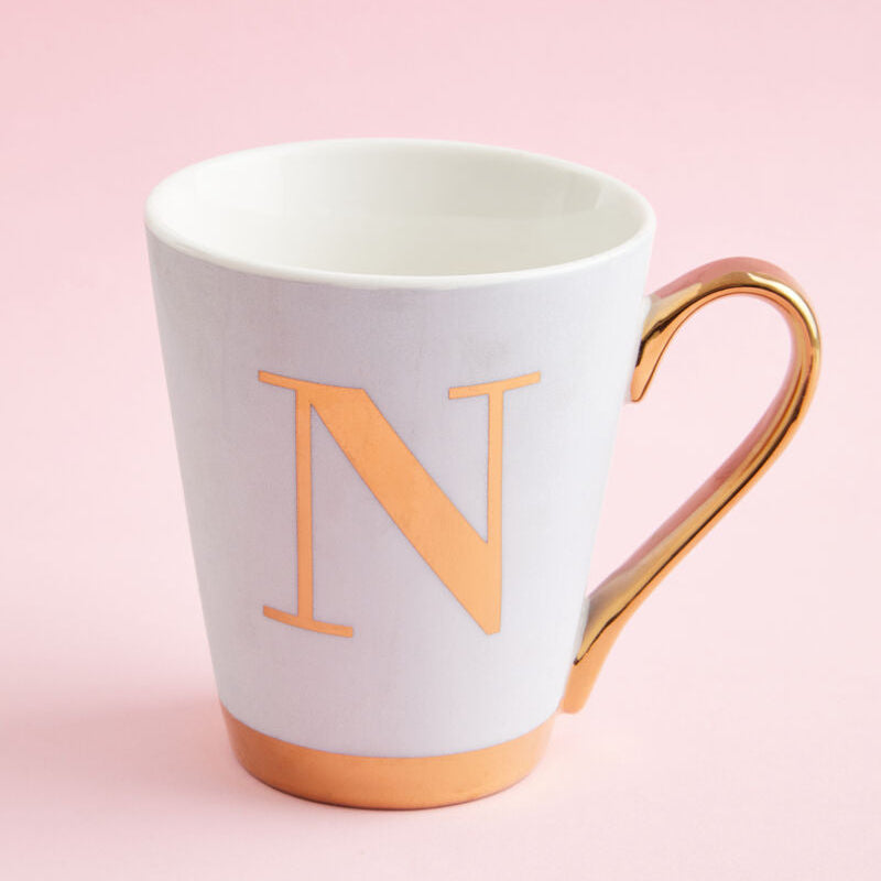 White mug with gold handle and letter &