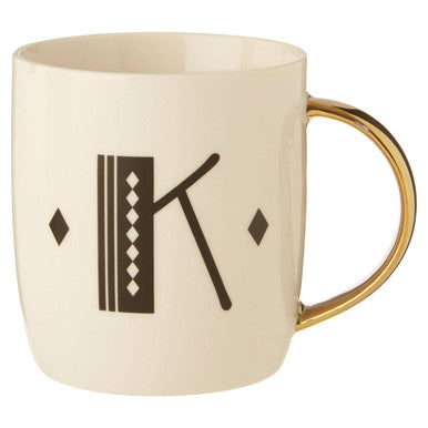 Beige mug with gold handle featuring a decorative letter &