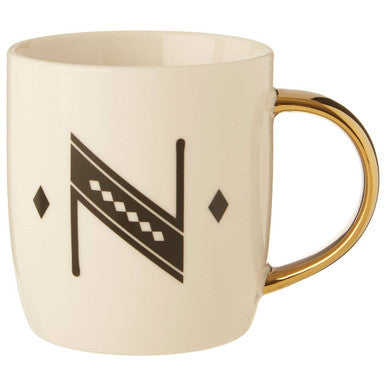 Beige mug with gold handle and black geometric design on a white background