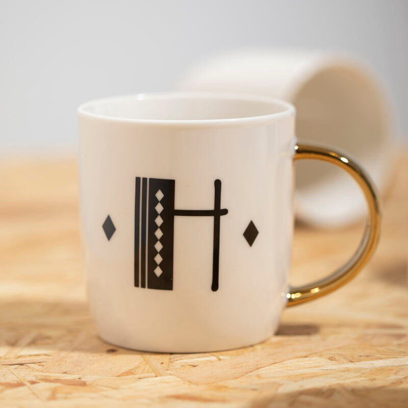 White mug with black geometric design on a wooden surface