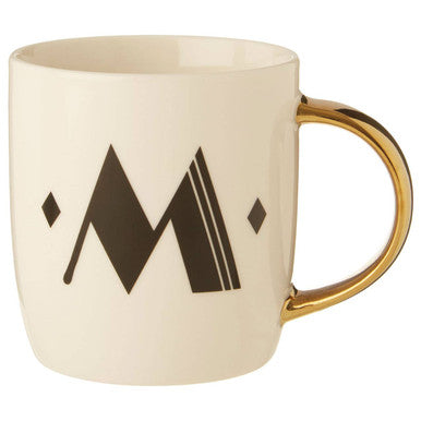 Beige mug with gold handle and black geometric design on a white background