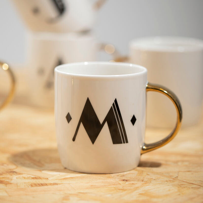 White mug with black mountain logo on a wooden surface