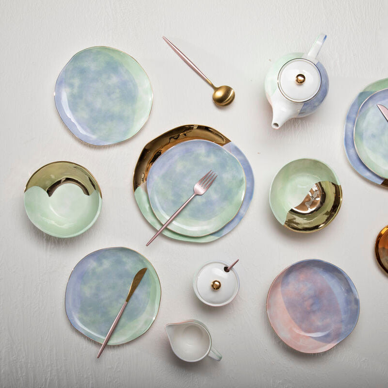 Collection of ceramic plates and tea sets on a light gray background