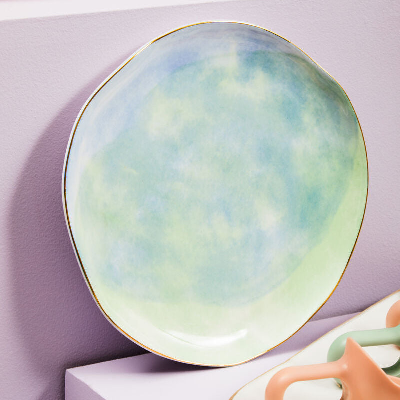 Round ceramic plate with a pastel gradient design on a white surface.